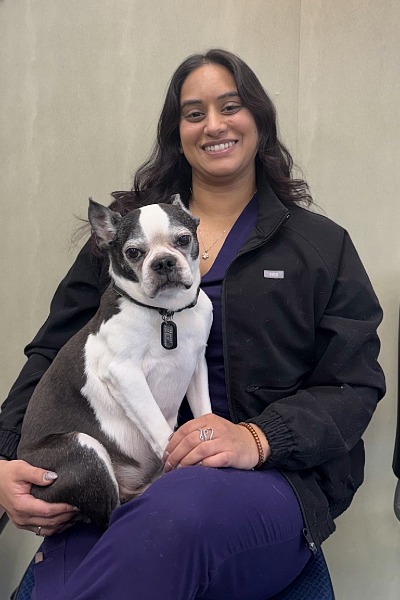female with long dark hair holding a Boston Terrier