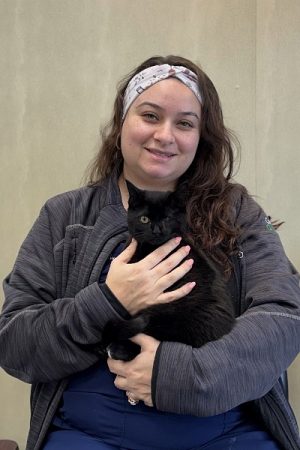 Female wearing a white bandana head band holding black cat